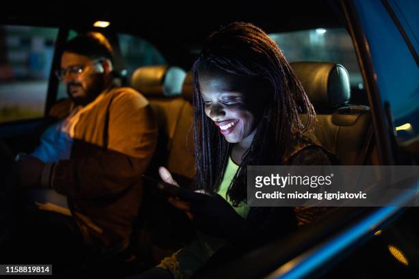 multi-ethnic friends ride sharing at night - ethnic woman driving a car stock pictures, royalty-free photos & images
