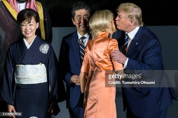 President Donald Trump kisses Brigitte Macron, wife of French President Emmanuel Macron , as Japan's Prime Minister Shinzo Abe and his wife Akie Abe...