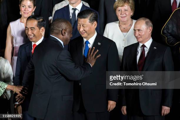 South Africa's President Cyril Ramaphosa waves as he walks past China's President Xi Jinping and Russia's President Vladimir Putin during a family...