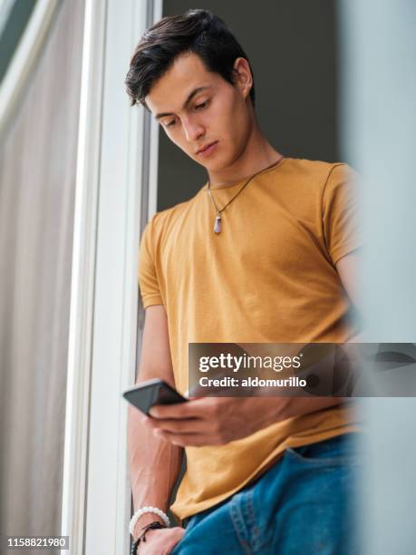 junger erwachsener, der auf ein smartphone mit ernstem ausdruck schaut - halbnahe-einstellung stock-fotos und bilder