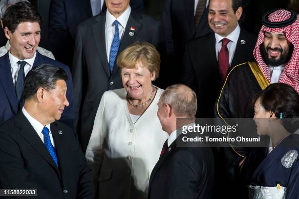 Germany's Chancellor Angela Merkel speaks to China's President Xi Jinping and Russia's President Vladimir Putin during a family photo session in...