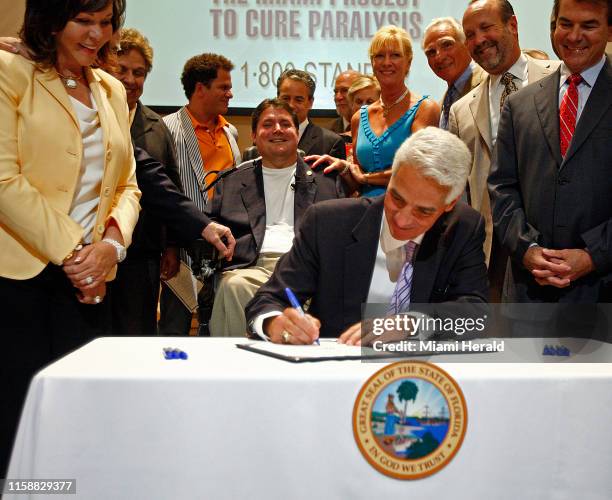 Marc Buoniconti, center, smiles as Gov. Charlie Crist ceremonially signs the bill HB 325 into law. Mary Anne Shula, left, and State Sen. Thad Altman,...