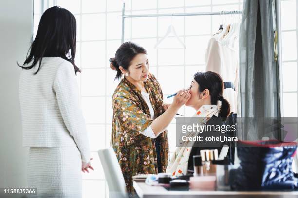 female hair and make up artist making up middle aged woman at studio - makeup artist stock pictures, royalty-free photos & images