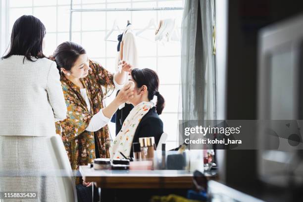 pelo femenino y artista de maquillaje maquillando mujer de mediana edad en el estudio - maquillador fotografías e imágenes de stock