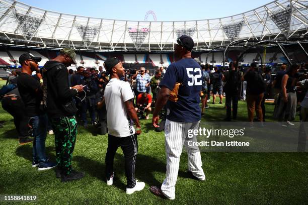 Raheem Sterling of England and Manchester City speaks with CC Sabathia of the New York Yankees on the field during previews ahead of the MLB London...