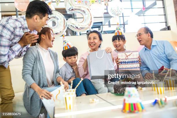 family members giving gifts to senior woman for her birthday - man giving cake candle stock pictures, royalty-free photos & images