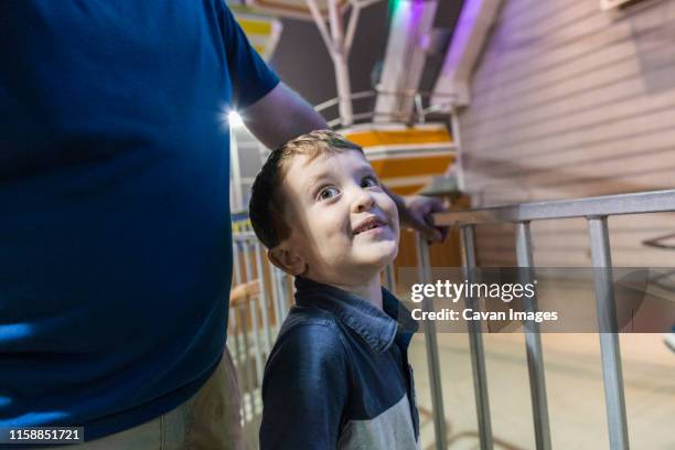 happy boy waits in line behind fence at amusement park with family - amusement park ticket stock pictures, royalty-free photos & images