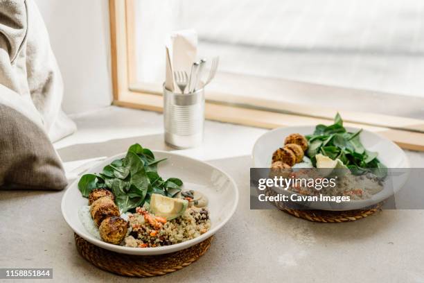 plates of vegan healthy food near window - pratos vegetarianos imagens e fotografias de stock