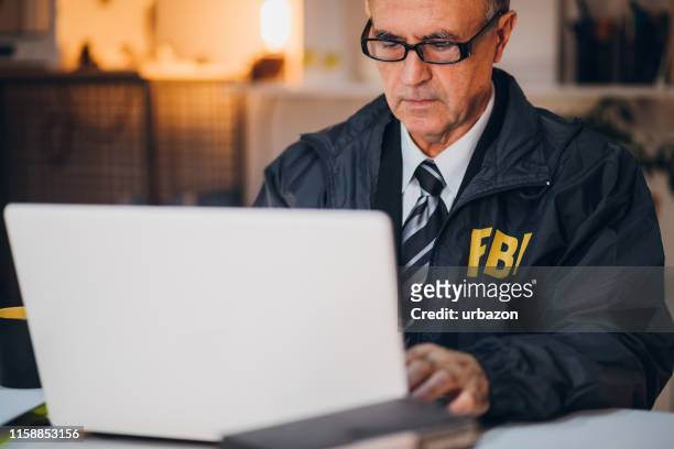 detective using laptop - fbi stock pictures, royalty-free photos & images