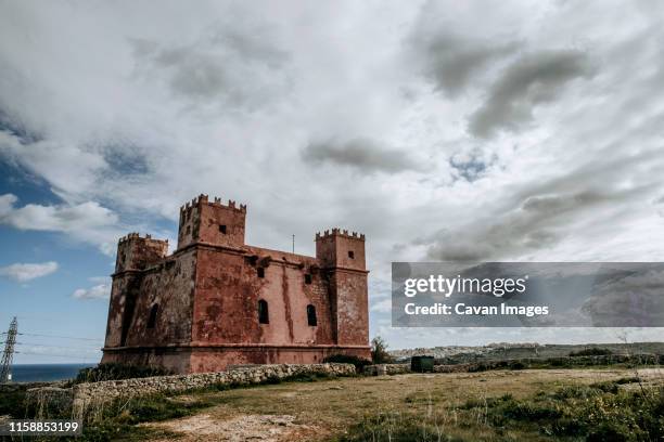 the medieval red tower on malta stands guard over the atlantic ocean - mellieha malta stock pictures, royalty-free photos & images