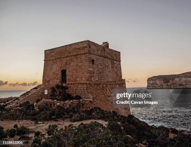 xlendi, malta stands guard over the island of gozo at sunset. - malta wandern stock-fotos und bilder