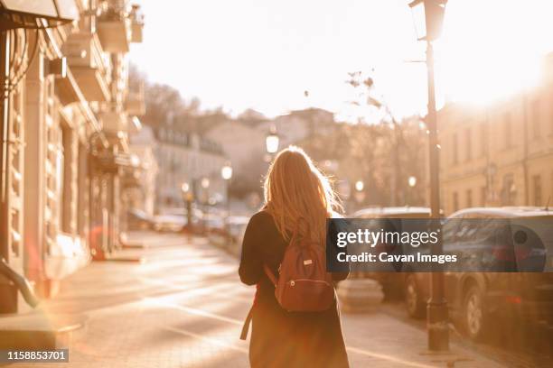 rear view of teenage girl with backpack walking on street - student day dreaming stock pictures, royalty-free photos & images