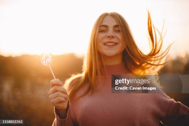 young happy woman holding lollipop while standing against sunset - golden hour stock pictures, royalty-free photos & images