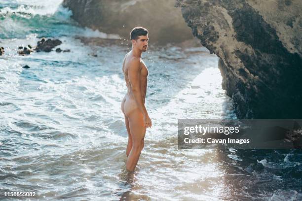 muscular and naked man walking along the seashore - beach bum imagens e fotografias de stock