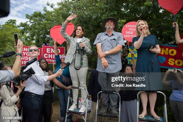 Democratic Presidential candidates, Sen. Kamala Harris and Sen. Kirsten Gillibrand stand on ladders to see over a fence into the grounds of a...