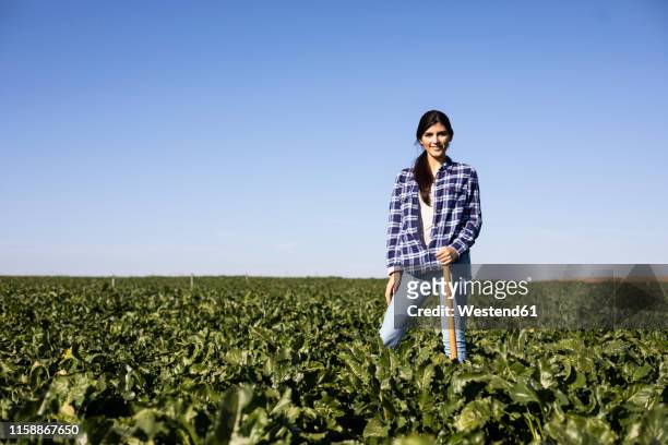 young woman farmer with hoe on field - farmer female confident stock-fotos und bilder