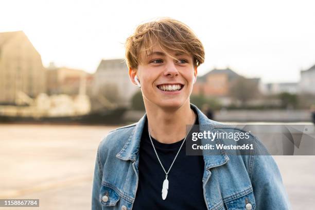 denmark, copenhagen, portrait of happy young man with earbuds in the city - 18 19 anni foto e immagini stock