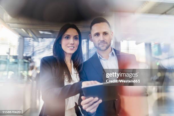 smiling businessman and businesswoman with tablet looking at a machine in modern factory - switzerland business stock pictures, royalty-free photos & images