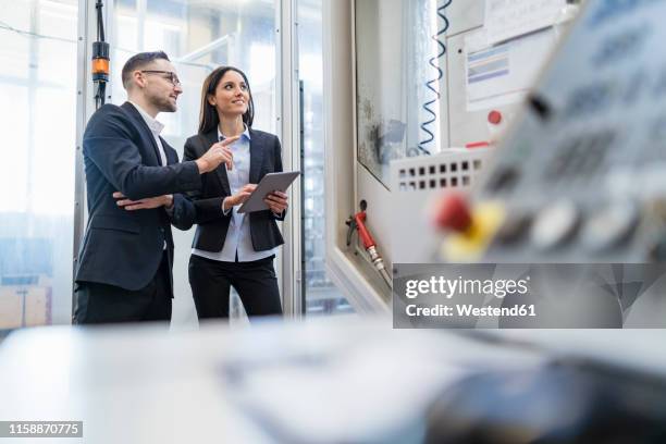 businessman and businesswoman with tablet talking in modern factory - switzerland business stock pictures, royalty-free photos & images