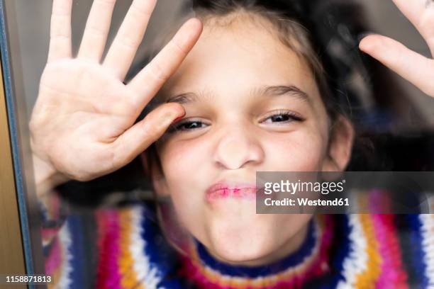 portrait of happy playful girl in striped pullover behind windowpane - kisses the hand stock pictures, royalty-free photos & images