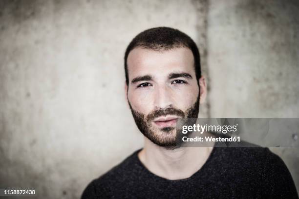 portrait of confident young man at concrete wall - entsättigt stock-fotos und bilder