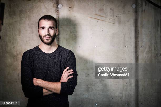 portrait of confident young man at concrete wall - entsättigt stock-fotos und bilder