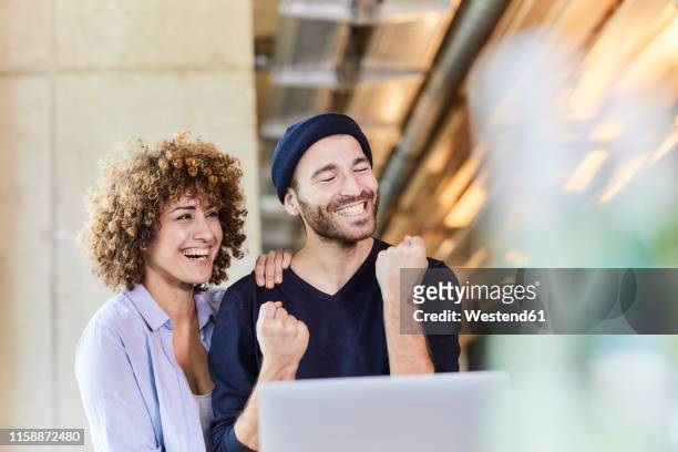 excited man and woman with laptop in modern office - business woman cheering stockfoto's en -beelden