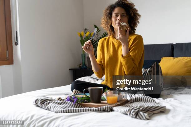 woman sitting on bed, having a healthy breakfast - vollkornbrot stock-fotos und bilder