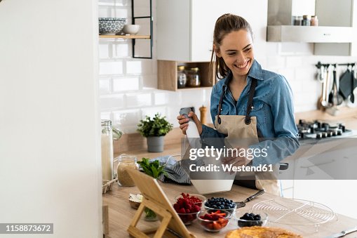 Young woman preparing a cream cake, using tablet Young woman preparing a cream cake, using tablet