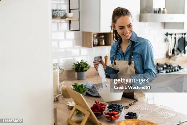 young woman preparing a cream cake, using tablet - female whipping 個照片及圖片檔