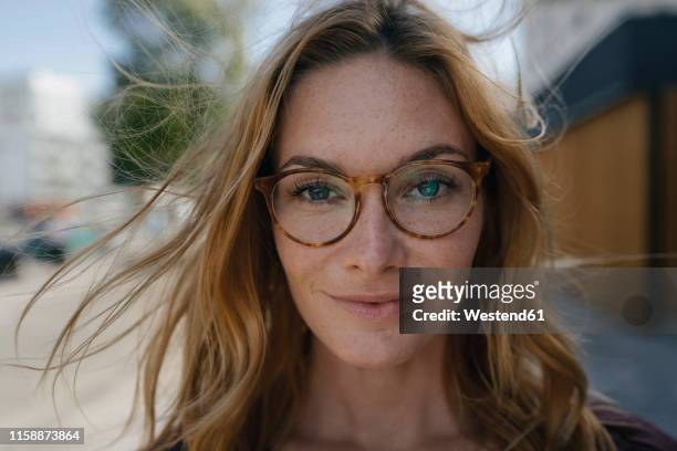 portrait of confident young woman with glasses and windswept hair - face sommersprossen stock-fotos und bilder