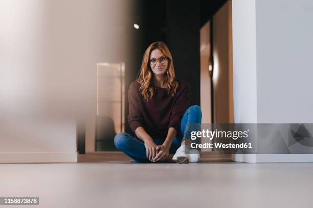 portrait of smiling businesswoman sitting on the floor - auf dem boden sitzen stock-fotos und bilder