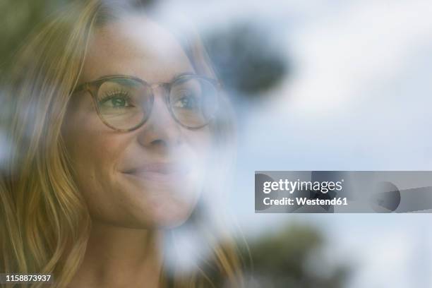 smiling young woman behind windowpane - anticipation face stock pictures, royalty-free photos & images