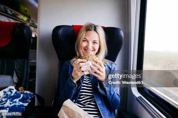 portrait of smiling blond woman travelling by train having a snack - blond women happy eating stock pictures, royalty-free photos & images