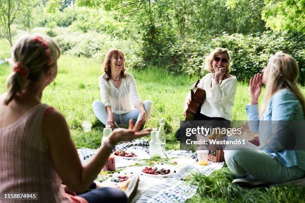 group of women with guitar having fun at a picnic in park - 4 life natural foods stock-fotos und bilder