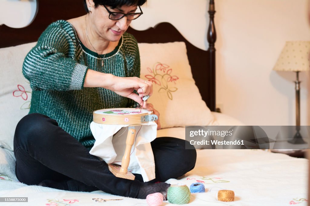 Woman embroidering sitting on bed at home