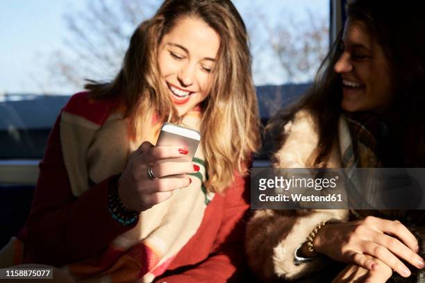uk, london, two happy women in underground train using cell phone - vie londres soleil photos et images de collection