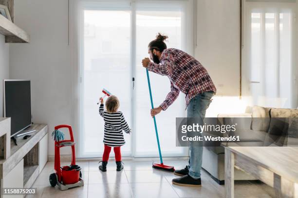 father and little daughter cleaning the living room together - städutrustning bildbanksfoton och bilder