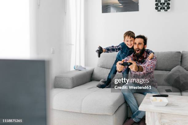 excited father and son playing computer game at home - arts related stock pictures, royalty-free photos & images