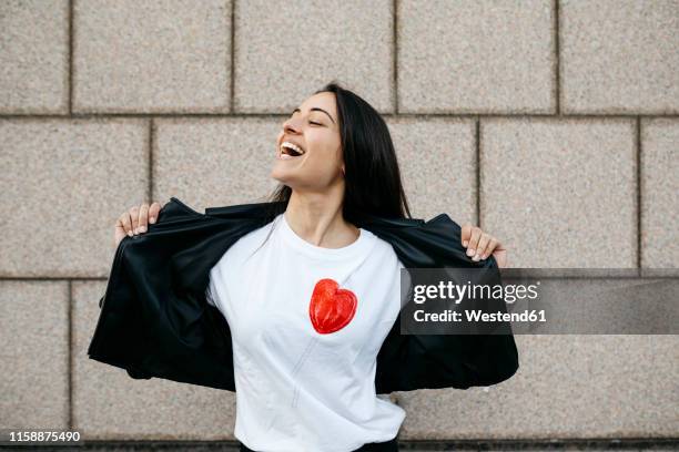 young woman opening her suit jacket on a wall in background - versierd jak stockfoto's en -beelden