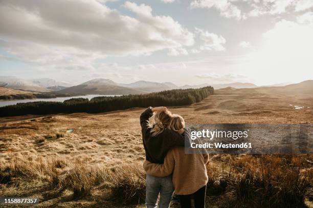 uk, scotland, loch lomond and the trossachs national park, rear view of female friends looking at view - femmes de dos enlacée photos et images de collection