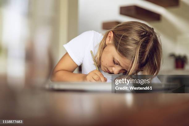 girl sitting at table writing into diary - kinder schreiben stock-fotos und bilder