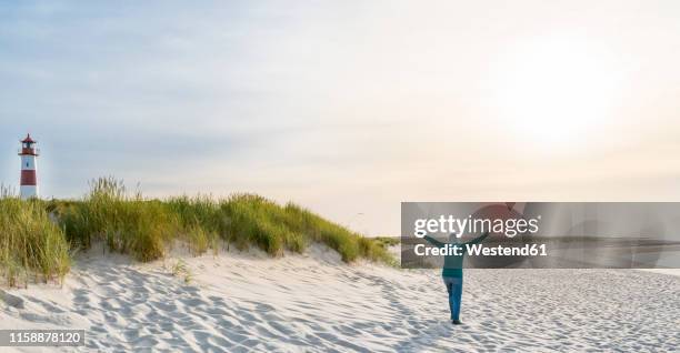 germany, sylt, north sea, happy woman strolling on sandy beach - região marítima do norte da alemanha imagens e fotografias de stock