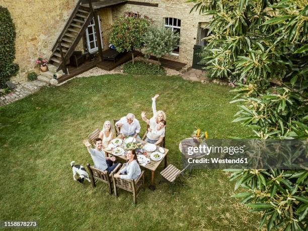 family eating together in the garden in summer - animal waving stockfoto's en -beelden