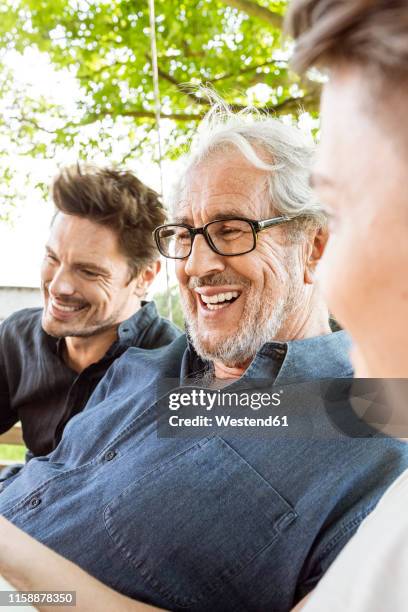 men of a family sitting on a swing bed ing the garden, talking - grandpa son stock pictures, royalty-free photos & images