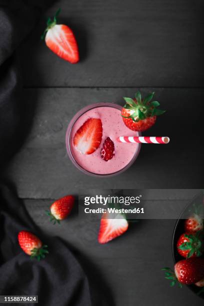 glasses of strawberry smoothie and strawberries on dark wood - strawberry smoothie stock pictures, royalty-free photos & images