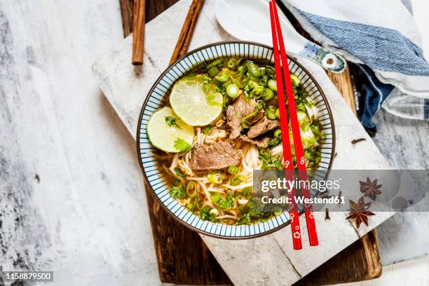 bowl of vietnamese pho with rice noodles, mung beans, cilantro, spring onions and limes - pho suppe stock-fotos und bilder