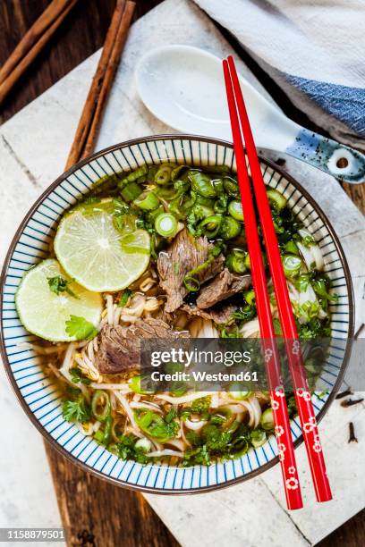 bowl of vietnamese pho with rice noodles, mung beans, cilantro, spring onions and limes - pho soup ストックフォトと画像