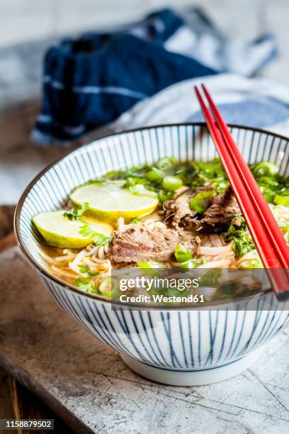 bowl of vietnamese pho with rice noodles, mung beans, cilantro, spring onions and limes - pho soup ストックフォトと画像