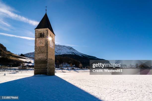 italy, venosta valley, sunken spire in frozen lago di resia in winter - schneebedeckt stock-fotos und bilder